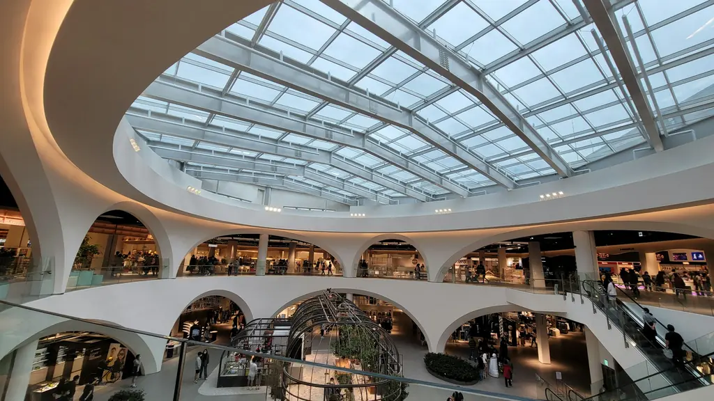 Shopping centre gallery under a glass roof, with an arcaded ground floor