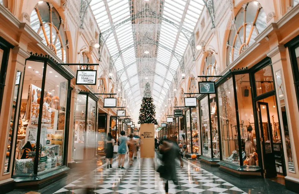 Glass-roofed shopping arcade with a Christmas tree and shoppers